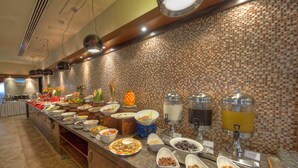 Un buffet con diversi cibi e un erogatore di succo.