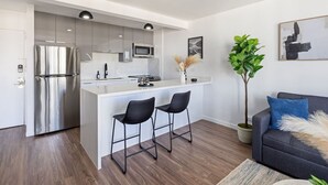 Ett modernt kök med en central köksö, rostfria vitvaror och svarta barstolar.