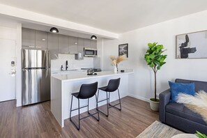 Eine moderne Küche mit einer zentralen Kochinsel, Edelstahlgeräten und schwarzen Barhocker.
