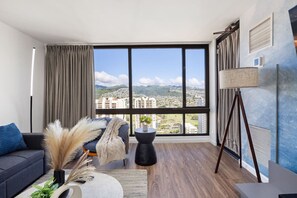 Ein modernes Wohnzimmer mit großem Fenster, einer Couch, einem Couchtisch und einer Lampe.
