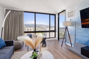 Ein modernes Wohnzimmer mit großem Fenster, einer Couch, einer Lampe und Blick auf eine Stadtansicht.