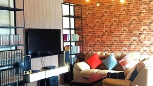 Un salon moderne avec un mur en briques, un téléviseur à écran plat, une bibliothèque et un fauteuil à bascule.