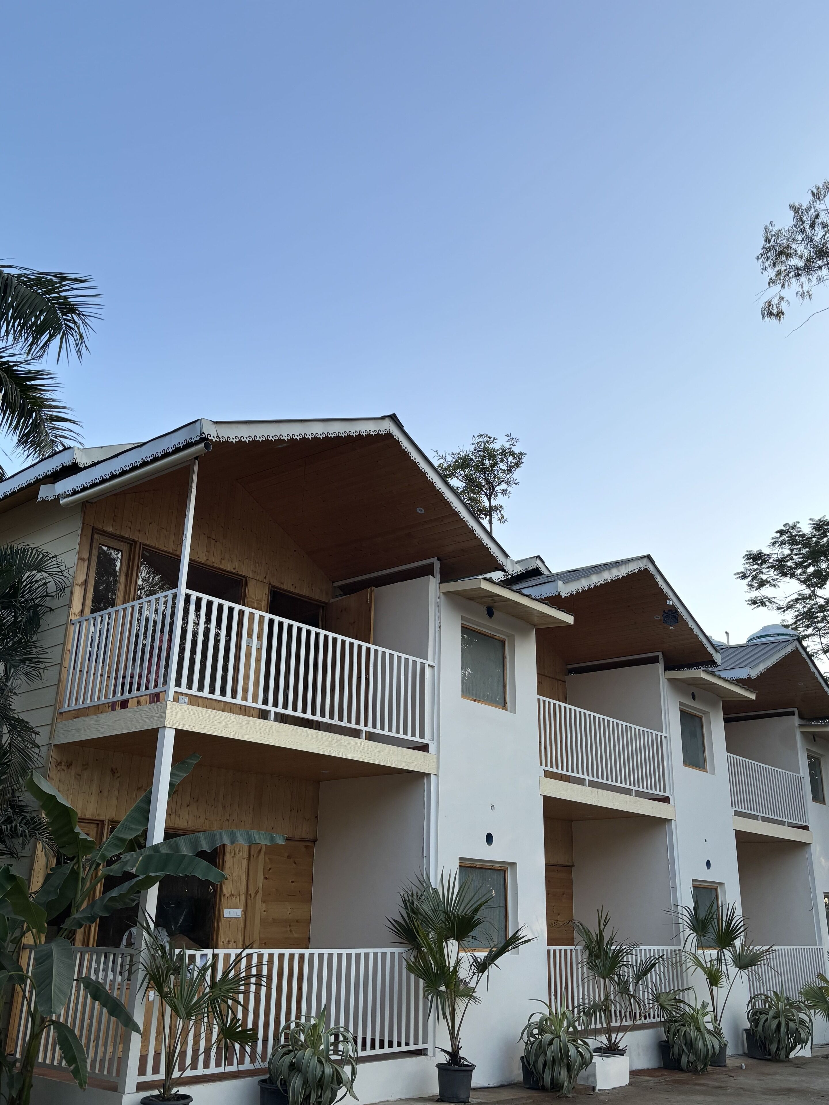 A multi-story building with balconies, wooden railings, and potted plants.