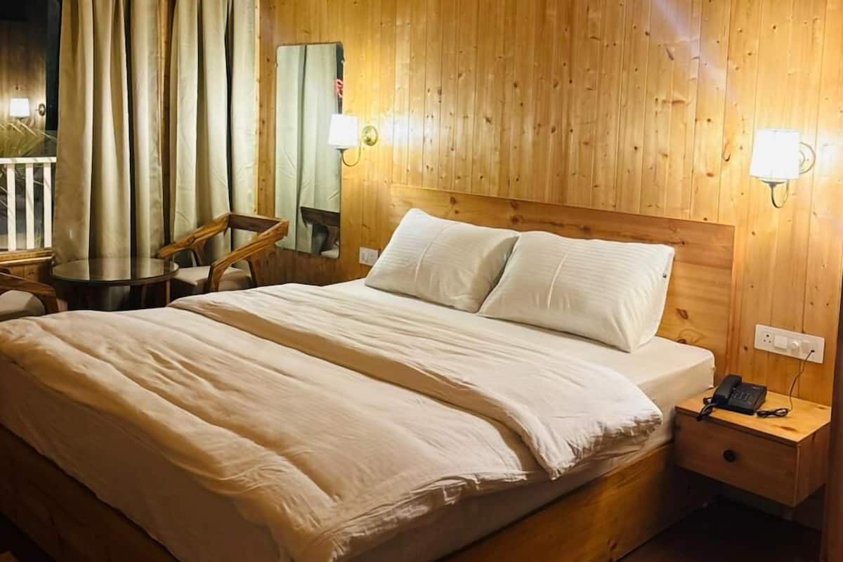 A wooden-paneled bedroom with a bed, bedside tables, a chair, and a small table.