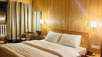 A wooden-paneled bedroom with a bed, bedside tables, a chair, and a small table.