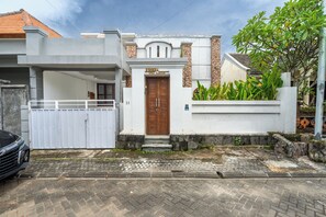 A modern house with a white exterior, a wooden door, and a small porch. - Bhiseka Villa Jimbaran by Aishwarya Bali (Jimbaran)