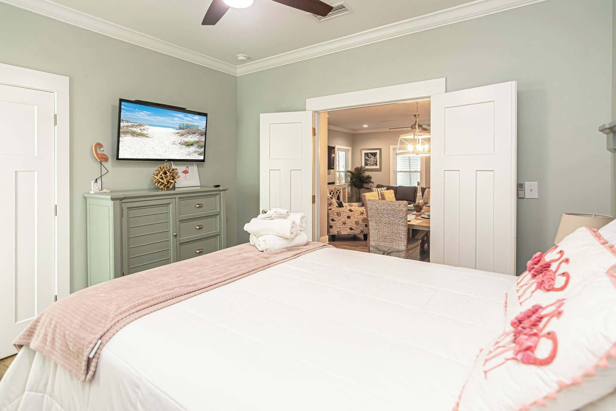 A bedroom with a bed, a TV, a dresser, and a desk with a chair.