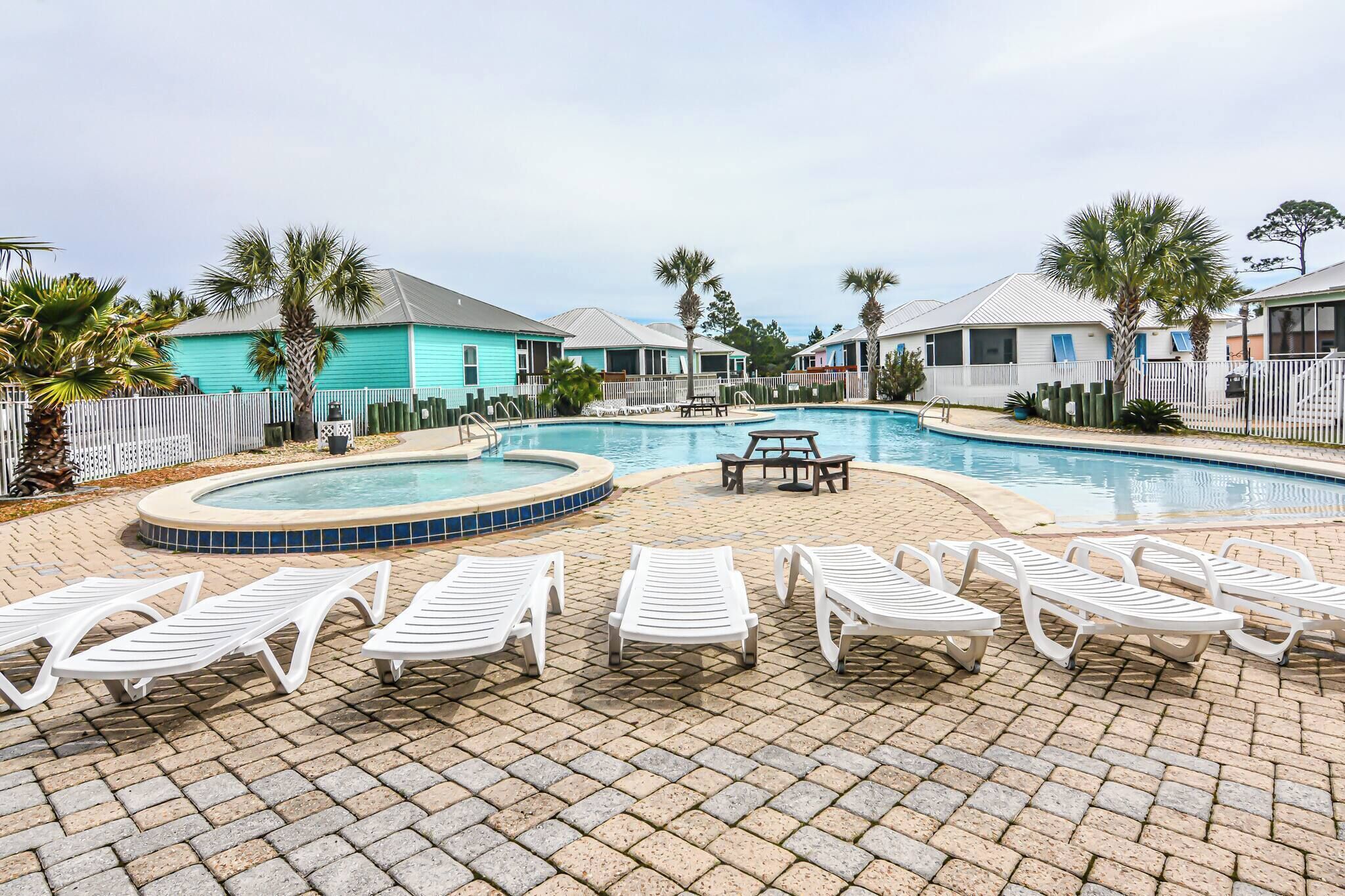 A pool area with lounge chairs, a hot tub, and a small table.