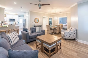 A modern living room with a sectional sofa, a wooden coffee table, and wicker chairs. - 5002 Rookery 3 Sea La Vie (Gulf Shores)