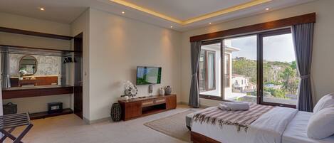 A modern bedroom with a large bed, a TV, a vanity, and a balcony with a city view.