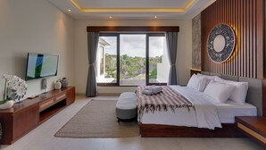 Une chambre à coucher moderne, dotée d’un grand lit, d’une télévision, d’une console en bois et offrant une vue sur l’extérieur.