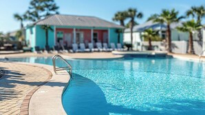 Piscina com espreguiçadeiras e um edifício ao fundo.