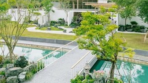 A modern building with a large glass facade, surrounded by landscaped gardens and a swimming pool. - Kiyomizu Onsen &Glamping Resort Saraburi (Nong Khae)