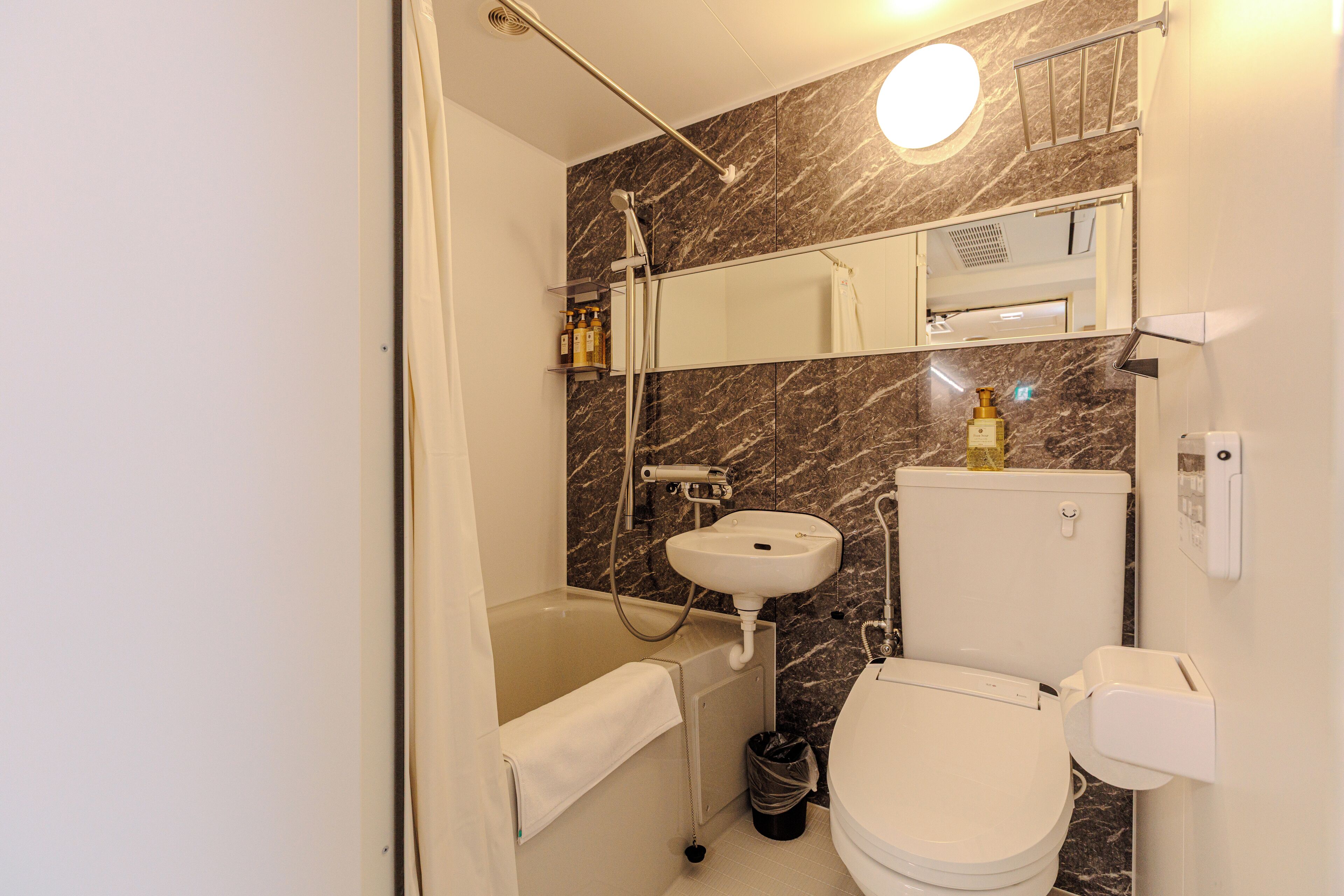 A bathroom with a bathtub, toilet, sink, and a mirror.