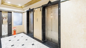 An interior hallway with marble flooring, two elevators, and a fire extinguisher. - Amemura Garden Hotel (Osaka)