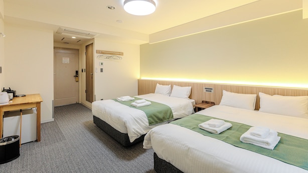 A hotel room with two beds, a desk, and a trash bin. - Amemura Garden Hotel (Osaka)