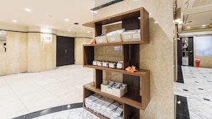 A hotel lobby with marble flooring, wooden shelving with baskets, and a reception area. - Amemura Garden Hotel (Osaka)