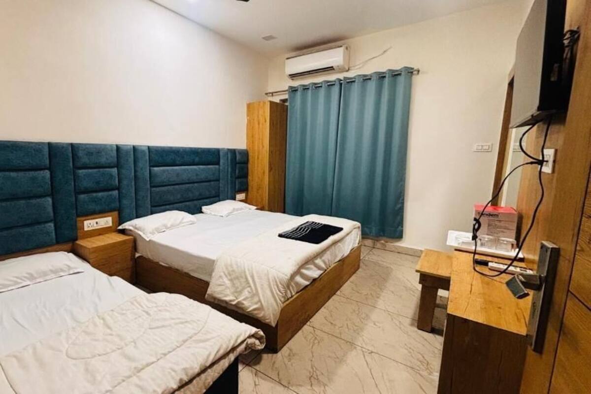 A room with two beds, a wooden headboard, a desk, and an air conditioning unit.