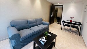 A modern living room with a grey sofa, a black coffee table, and a dining area with a small table and chairs.