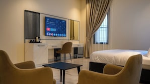Habitación de hotel con cama, escritorio, silla y televisor montado en la pared.