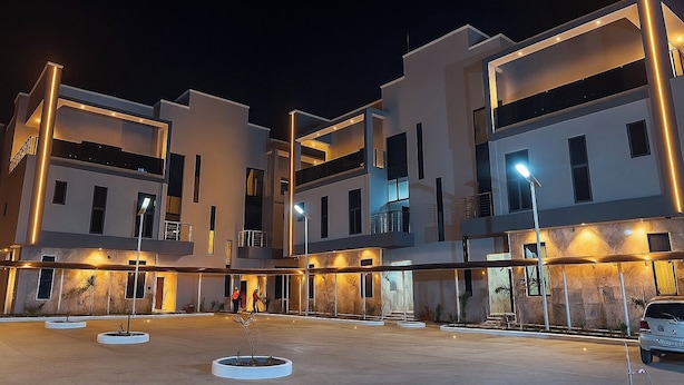 Un edificio moderno de varios pisos con balcones iluminados y un patio central.