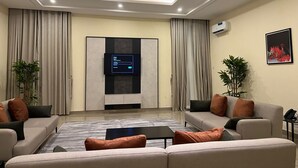 Una sala moderna con un conjunto de sofás, una mesita de centro y un televisor de pantalla plana montado en la pared.