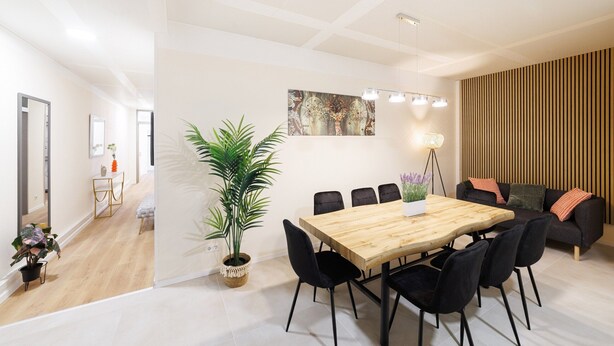 A modern dining area with a wooden table and black chairs, a potted plant, and a sofa with cushions. - Modern New 120m2 Apartment City Center KaDeWe /ZOO (Berlin)