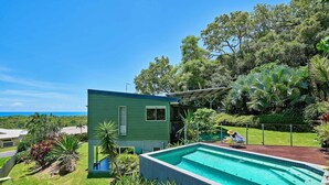 A house with a swimming pool, surrounded by lush greenery and a view of the ocean. - Oceanview Family Retreat w/ Private Pool & Fast WiFi (Palm Cove)