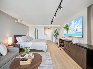 A modern hotel room with a bed, a sofa, a desk, and a TV. - 42F Coastal Chic Retreat -Elegant Oceanview Living (Honolulu)