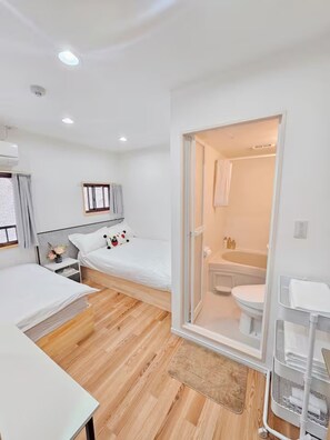 A modern hotel room with a bed, bedside table, and a bathroom visible through an open door. - Asakusa hanabi (Tokyo)