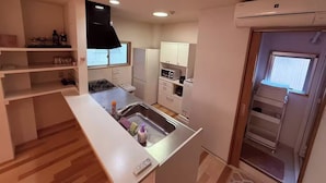 Une cuisine compacte dotée d’une cuisinière intégrée, d’un évier et de meubles blancs.