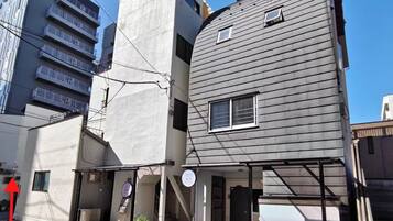 A multi-story building with a flat facade, a bicycle parked outside, and a red arrow indicating a direction.