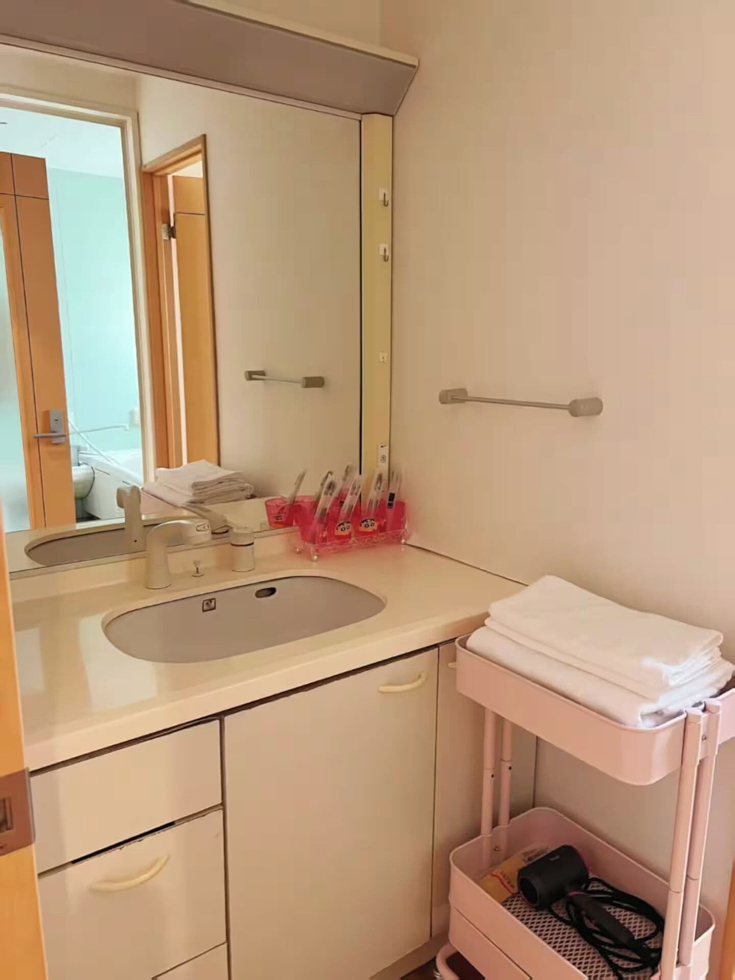 A bathroom with a sink, mirror, towel rack, and storage cabinet.