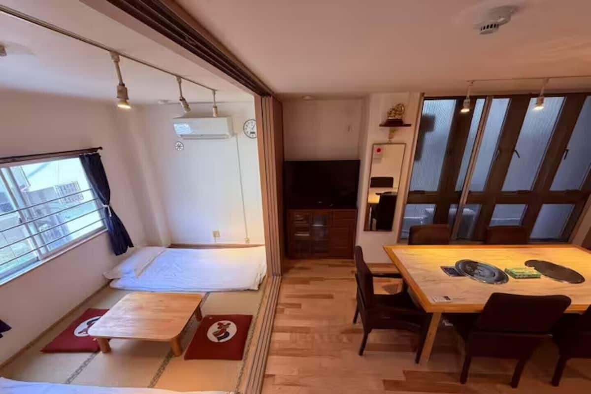 A compact room with a bed, a dining table, and a small kitchen area.
