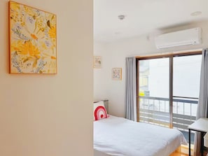 Une chambre d’hôtel équipée d’un lit, d’une table, d’un appareil de climatisation et d’un balcon avec vue.