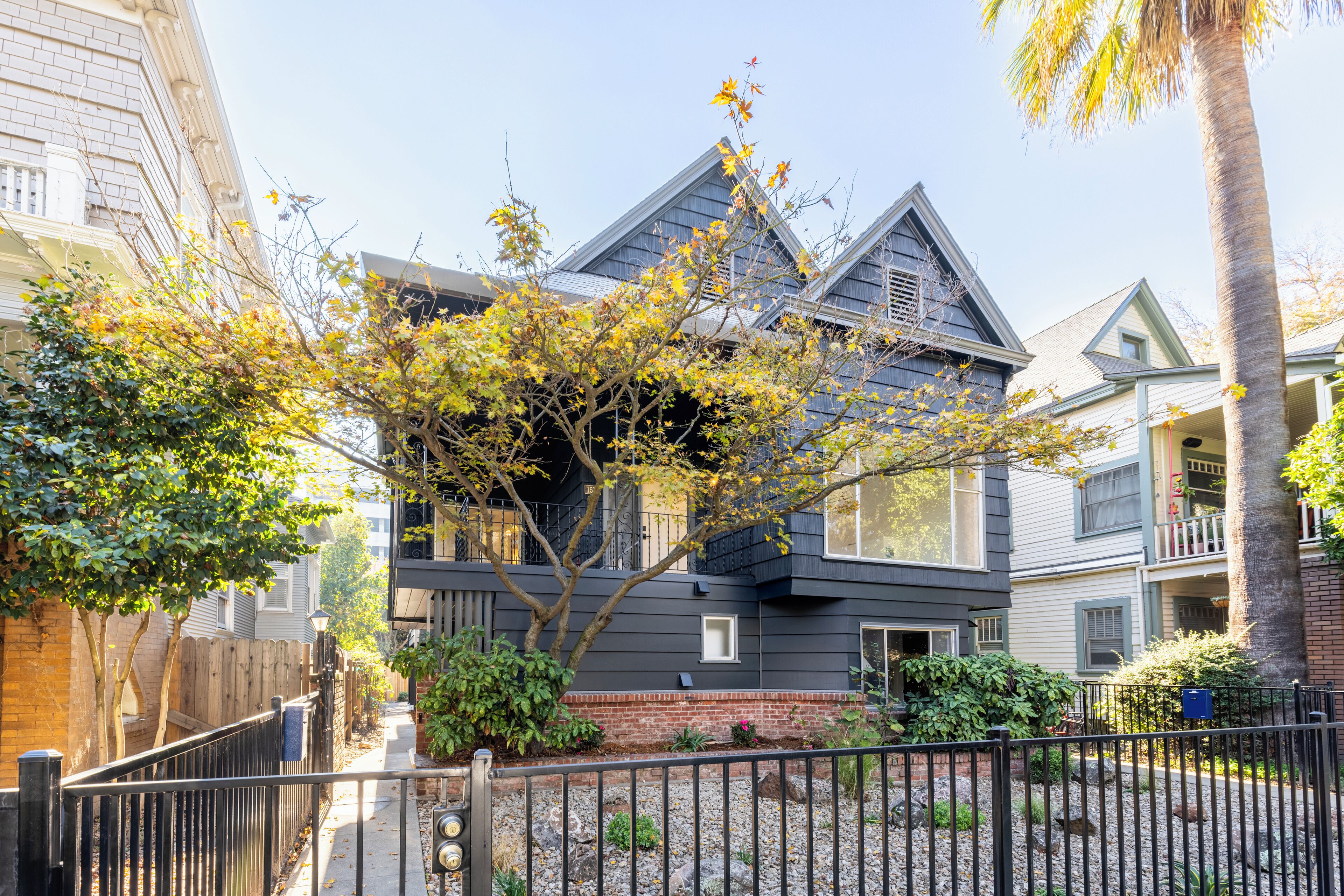 A two-story house with a dark gray exterior, a brick foundation, and a small front porch.