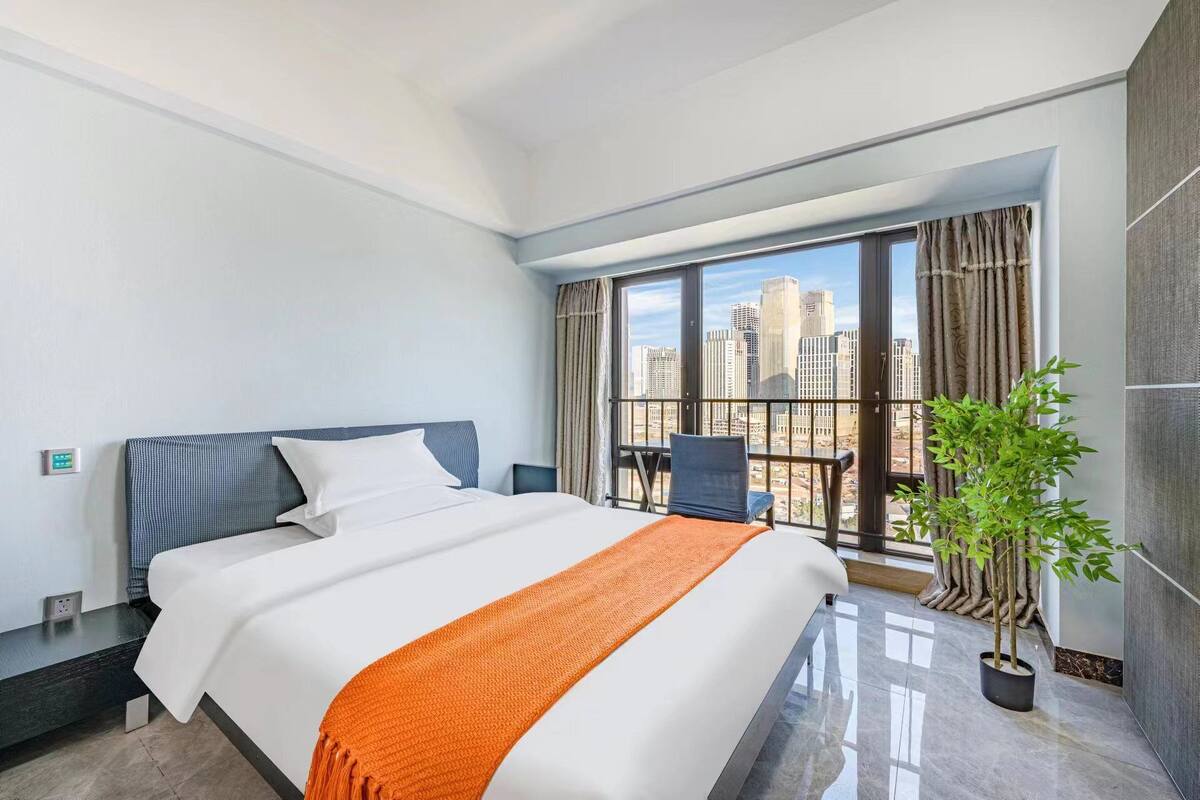 Ein modernes Hotelzimmer mit einem großen Bett, einem Balkon mit Blick auf die Stadt und einem Topfpflanzen.