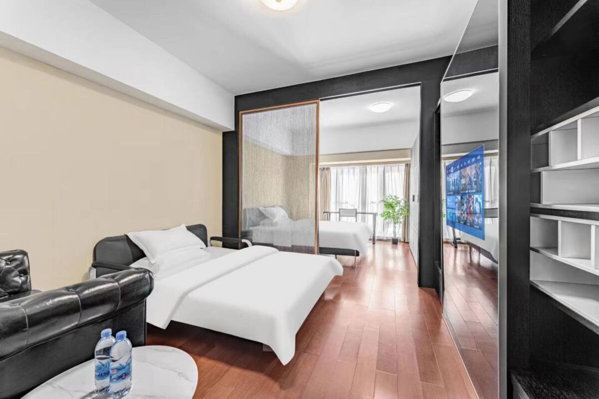 Ein modernes Hotelzimmer mit Bett, einer Sitzecke mit Tisch und einem Fernseher.