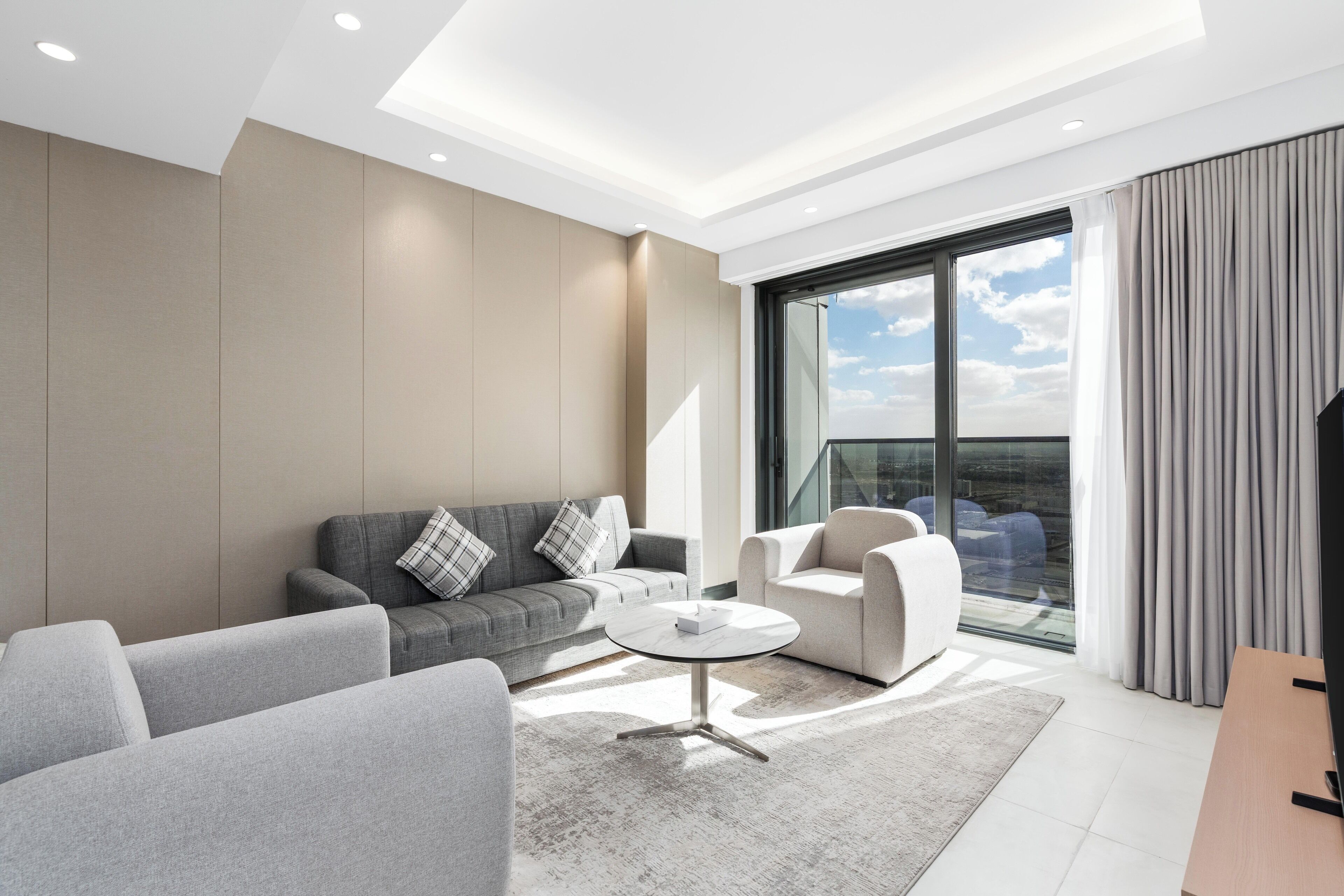 Ein modernes Wohnzimmer mit einer Couch, Sesseln, einem Couchtisch und einem großen Fenster mit Blick.