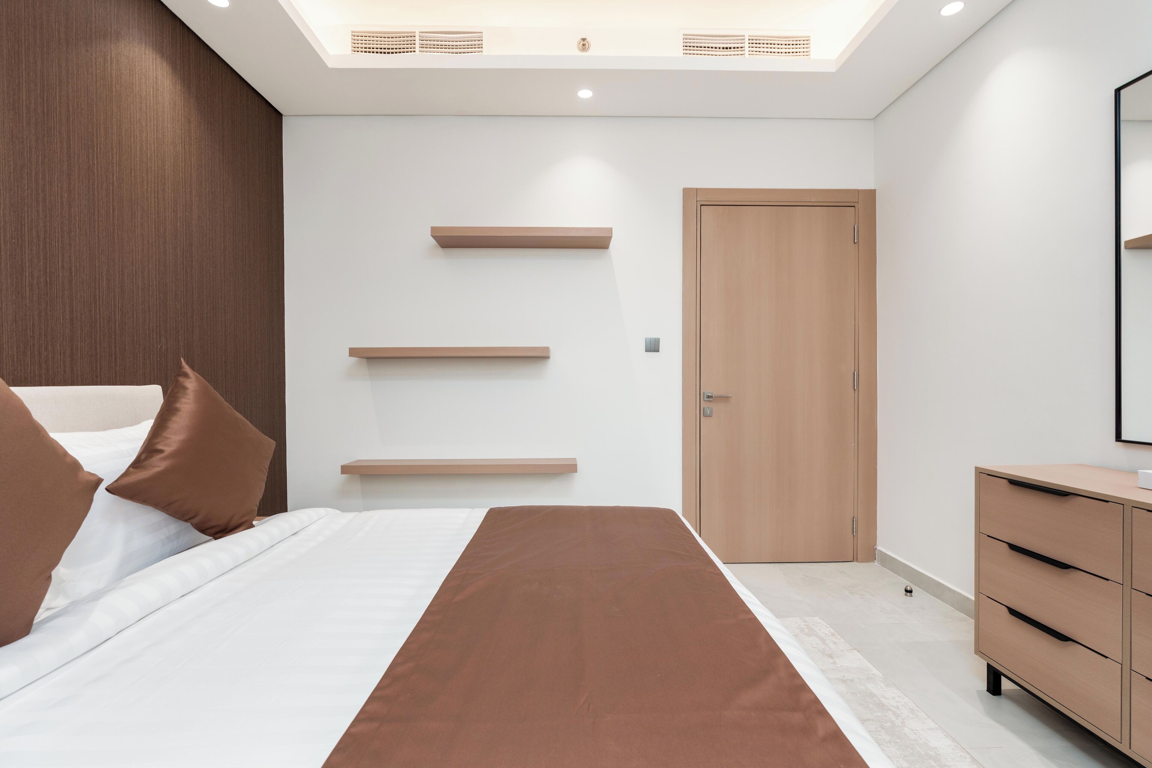 Une chambre à coucher moderne avec un lit, une armoire en bois et des étagères intégrées.