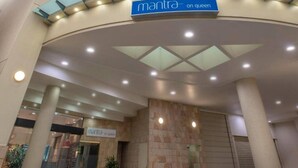 Une entrée moderne d’un immeuble, avec une enseigne indiquant « Mantra on Queen ».
