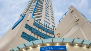 Un hotel de gran altura con un cartel llamativo que dice 'mantra on queen' en la entrada.