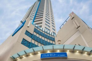 Ein Hochhaus-Hotel mit einem auffälligen Schild mit der Aufschrift 'mantra on queen' am Eingang.