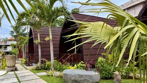 A modern building with a dark brown roof, surrounded by lush greenery and a stone pathway. - Dalung Tropical (Dalung)