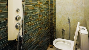 Ein Badezimmer mit Dusche, Toilette und einer Wand mit einem gemusterten Fliesenmuster.