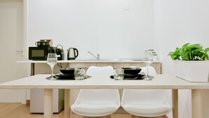 Une cuisine moderne avec une table à manger pour deux personnes, équipée d’un four à micro-ondes, d’une bouilloire et d’une plante en pot.