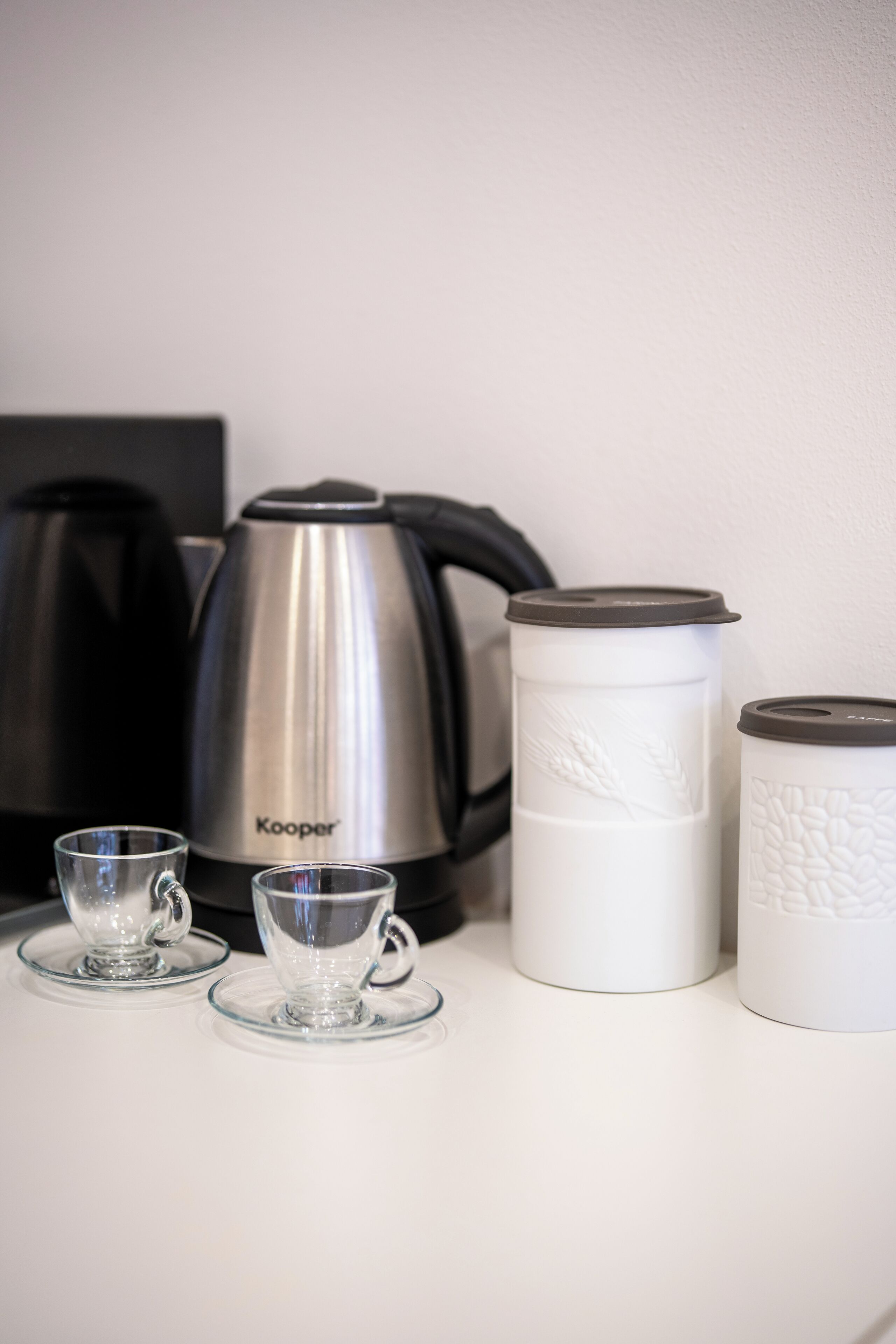 A coffee maker, two cups, and two thermoses on a table.