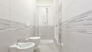 Une salle de bain moderne avec une douche à parois de verre, deux vasques et un porte-serviettes.