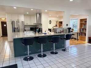 A modern kitchen with a central island, bar stools, stainless steel appliances, and a bookshelf. - Cottonwood Heights Escape/Minutes to Trails & Views (Cottonwood Height)