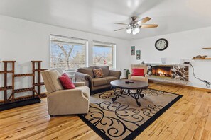 A living room with a fireplace, a ceiling fan, and a clock on the wall. - Cottonwood Heights Escape/Minutes to Trails & Views (Cottonwood Height)